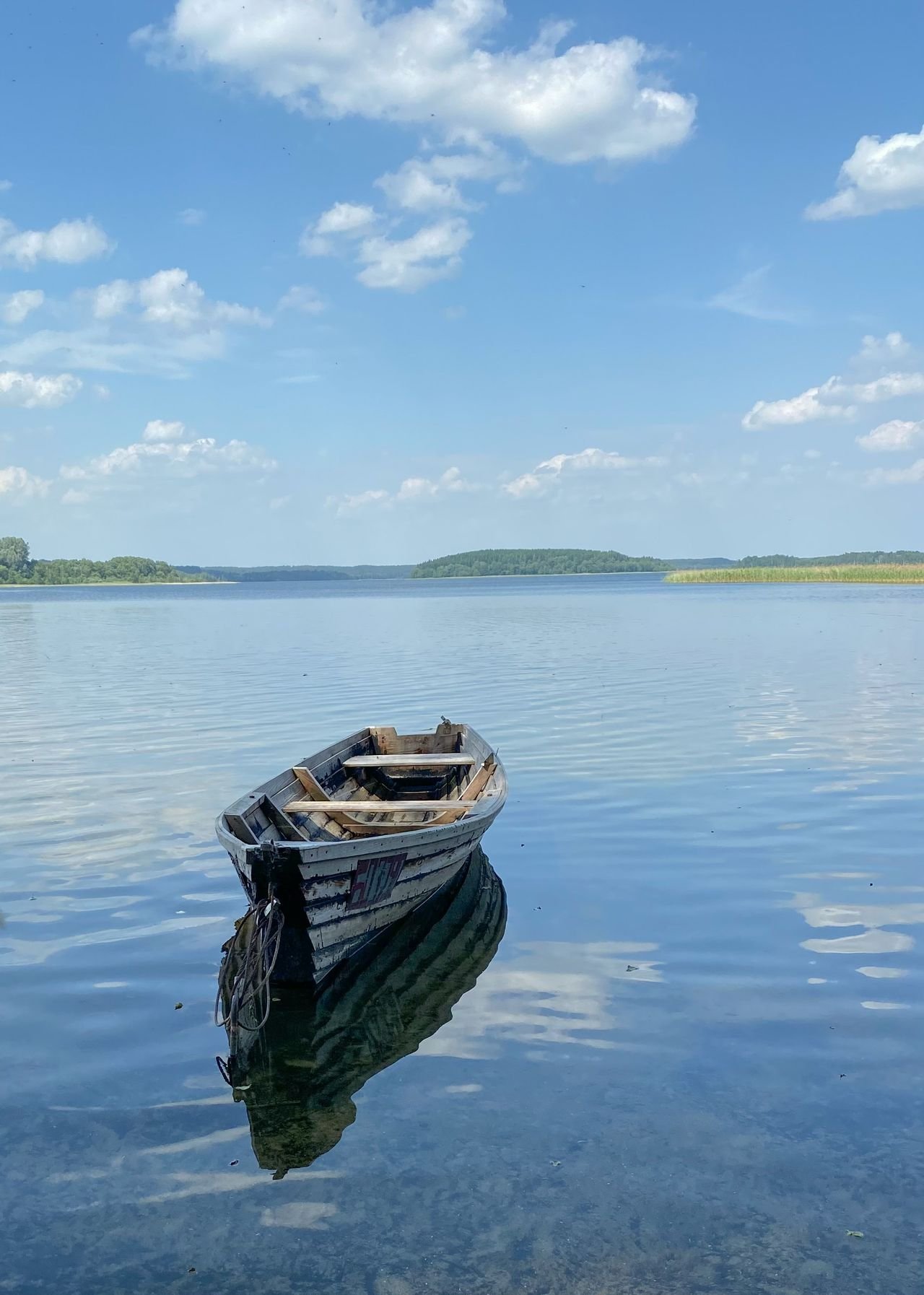 A small boat on a calm lake under a blue sky