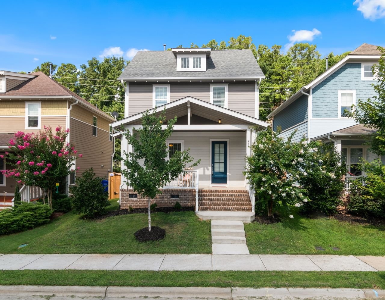 A two-story family house with a front porch and lawn